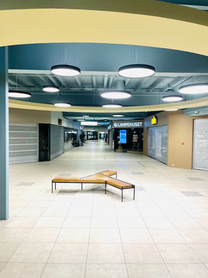 Lyst og moderne interiør i offentlig bygg med benker, buet tak og integrert belysning.