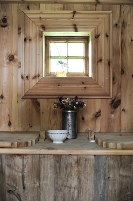 Lite baderom med trepanel på vegger og tak, speil og servant i rustikk stil.