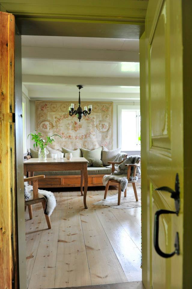 Åpen grønn dør som leder inn til en lys og hyggelig stue med tregulv og spisebord.